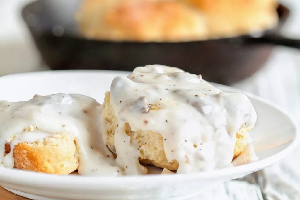 Two buttermilk biscuits covered in gravy on a white plate--an essential food in Savannah Georgia