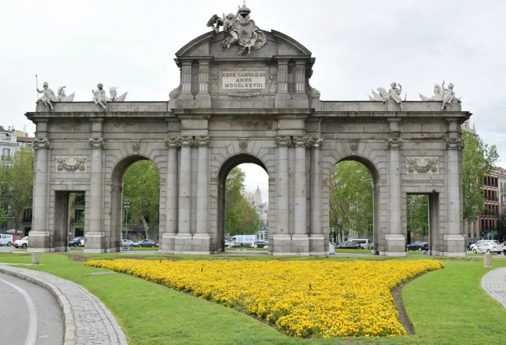 blooming yellow flowers in front of a beautiful stone gate in madrid spain