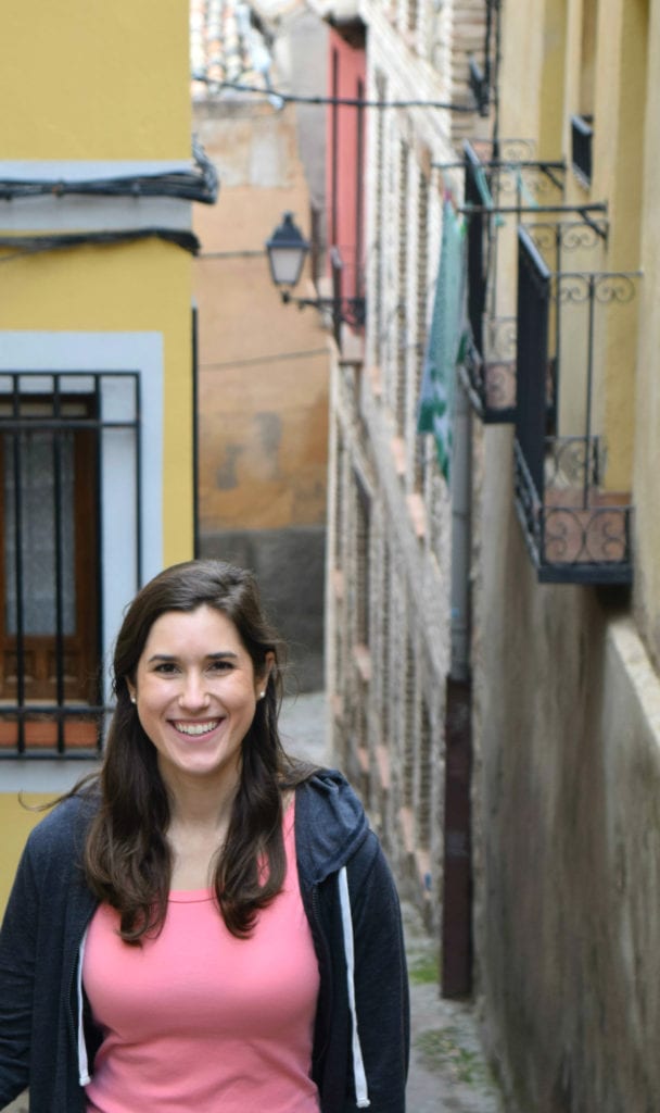 Kate Storm in a pink shirt standing in front of a yellow building on a day trip to Toledo