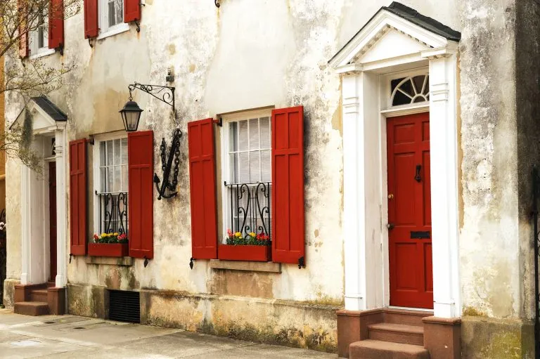 Photo of a white stucco building in charleston sc with red shutters. you'll see views like this when exploring what to do in charleston when it rains