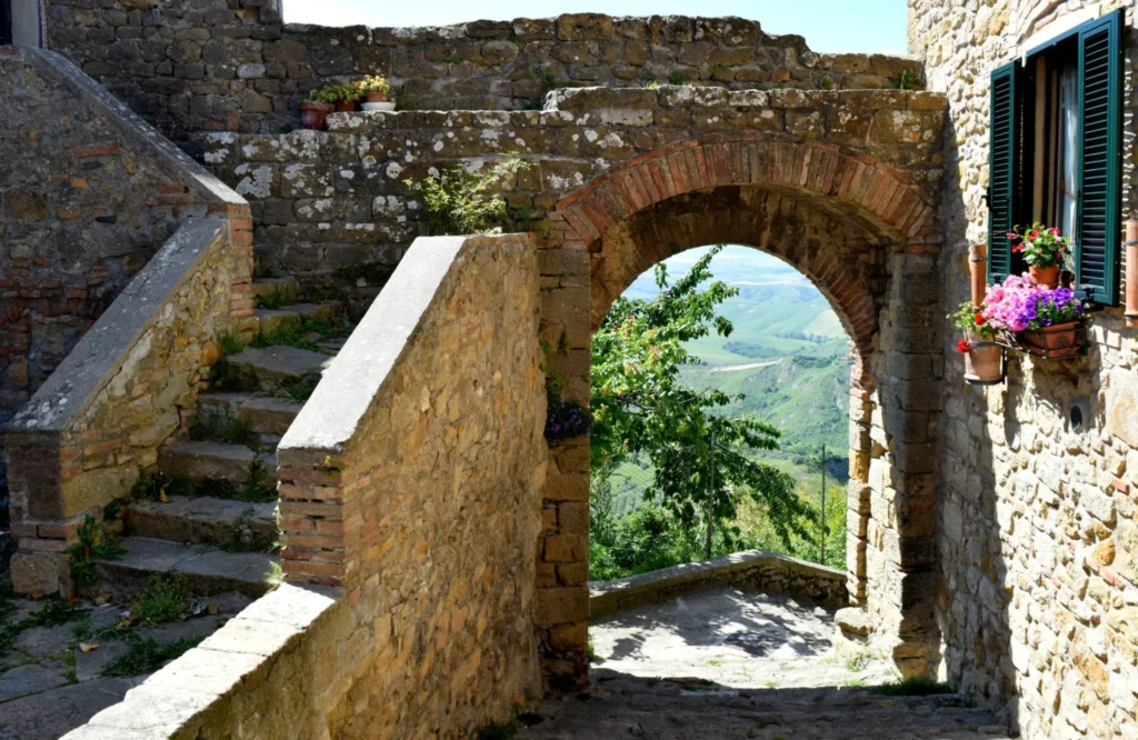 stone archway leading to views of tuscany with a stone staircase to the left, a quiet place to visit in volterra italy