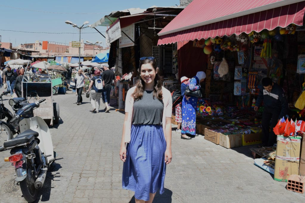 kate storm standing in marrakech medina, shopping for souvenirs that will add to the trip to morocco cost but be worth it