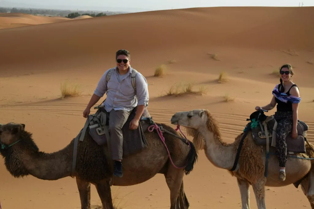 kate storm and jeremy storm on camels in the sahara desert, one of the most expensive trip to morocco costs and worth every penny