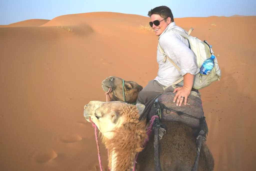 jeremy storm riding a camel on a sahara desert tour in morocco during a backpacking 6 month round the world trip