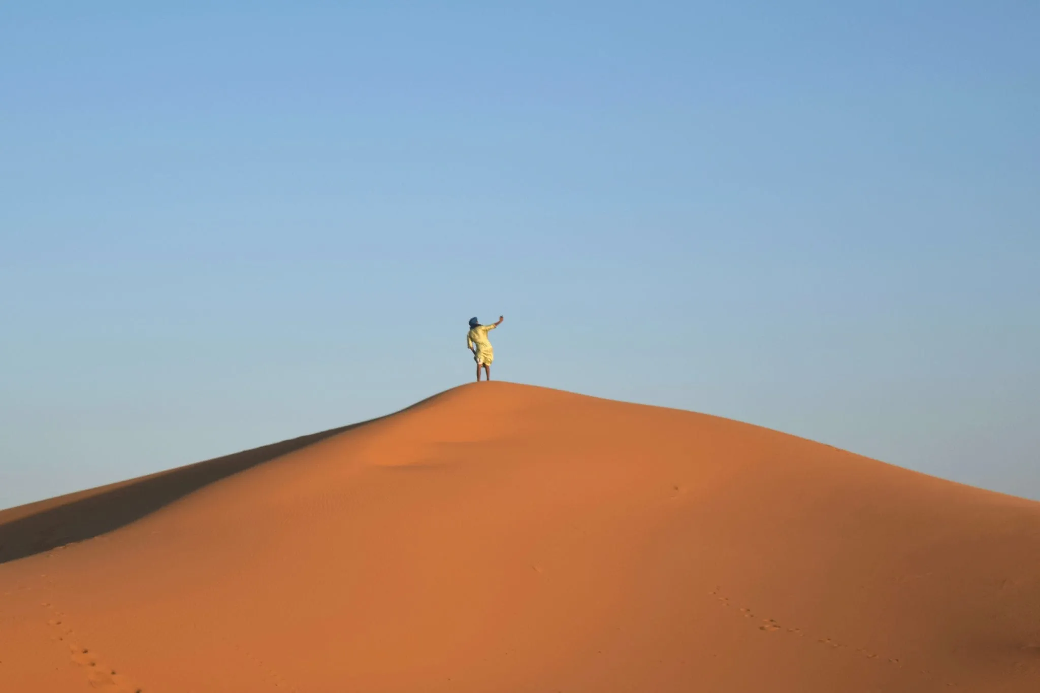 man taking a selfie from a sand dune during a sahara desert tour morocco