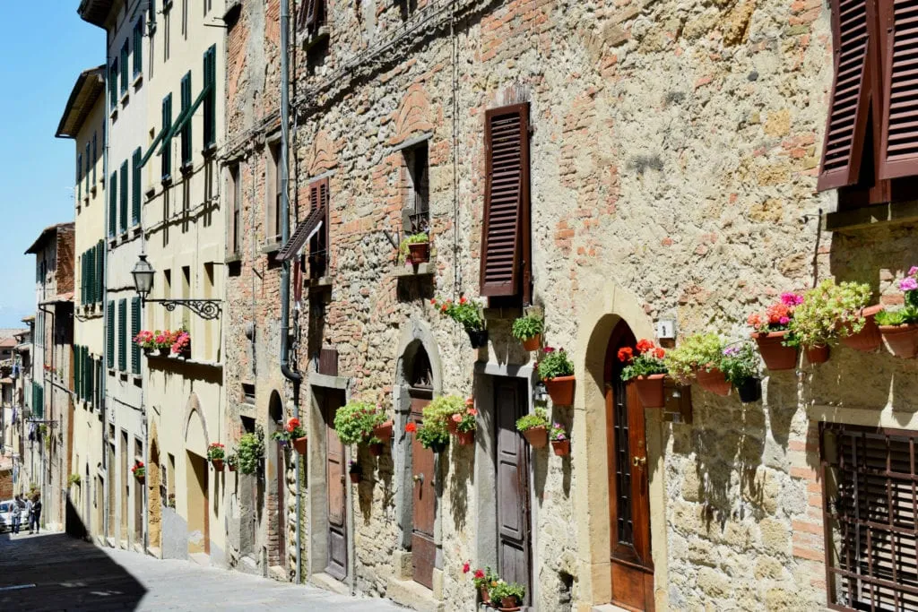 stone buildings with pots of flowers by the doors in tuscany