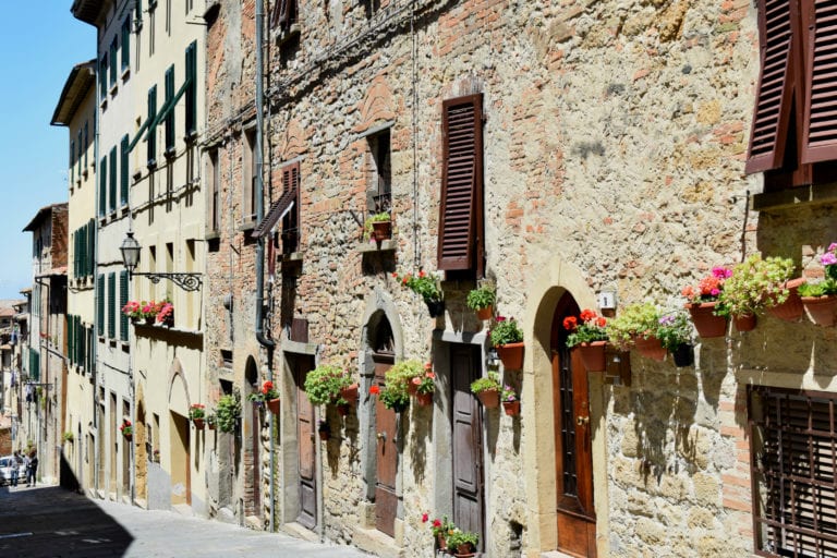 stone buildings with pots of flowers by the doors in tuscany, as seen during long term travel cheaper than you think