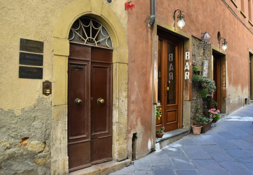 small street with closed doors and a coffee bar in volterra italy