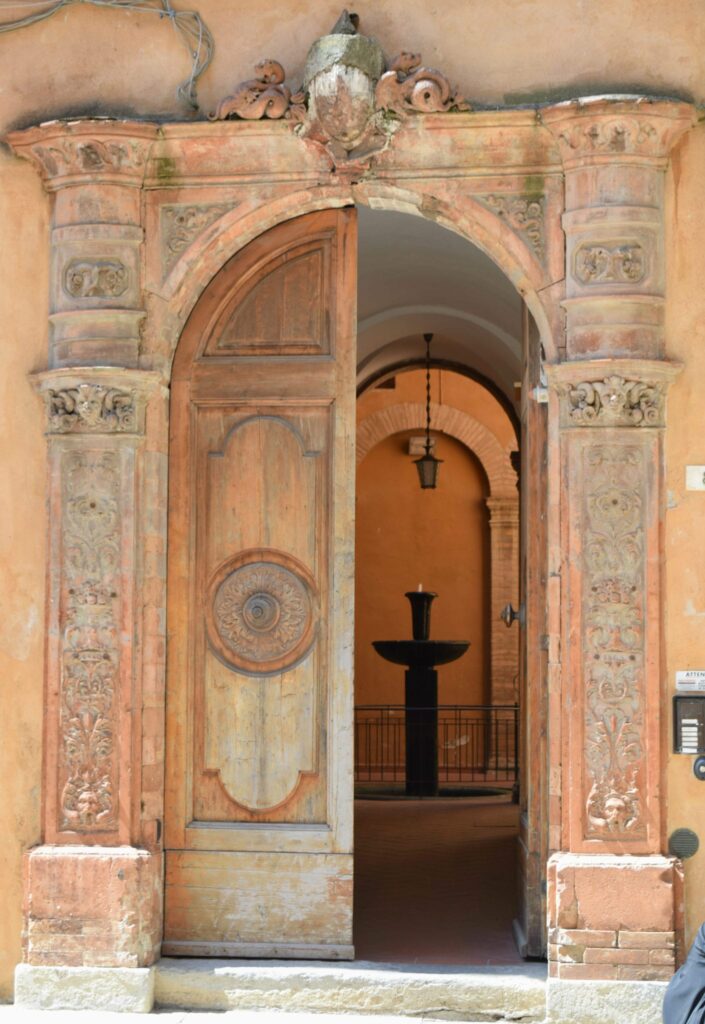 open door in volterra italy with a fountain showing in the interior courtyard