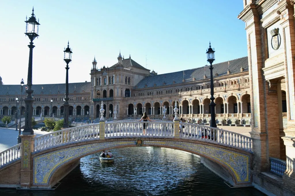 Kate Storm standing on a bridge in Seville Spain with her back to the camera--Seville makes an excellent stop on a Europe road trip!