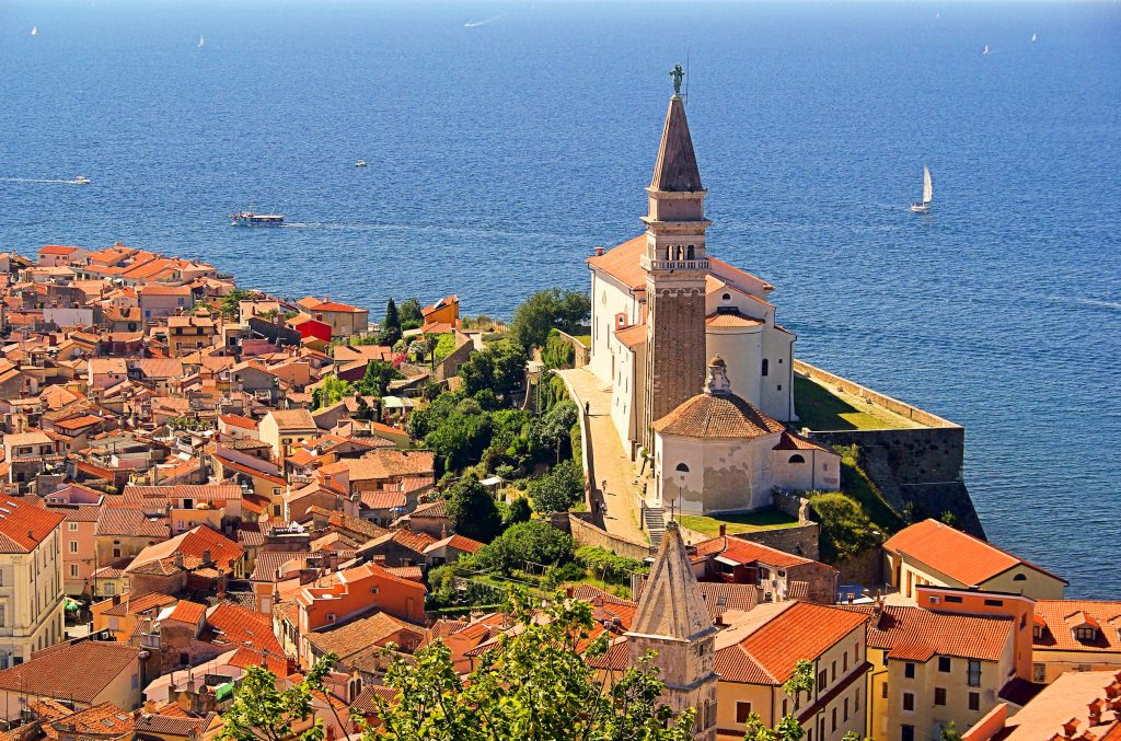 photo of piran slovenia from above with sailboat in the background
