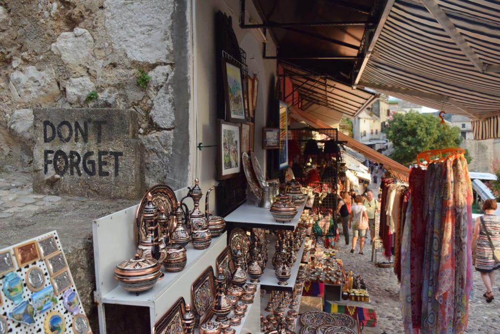 copper souvenirs for sale in mostar bosnia and herzegovina, "don't forget" is written on a stone block