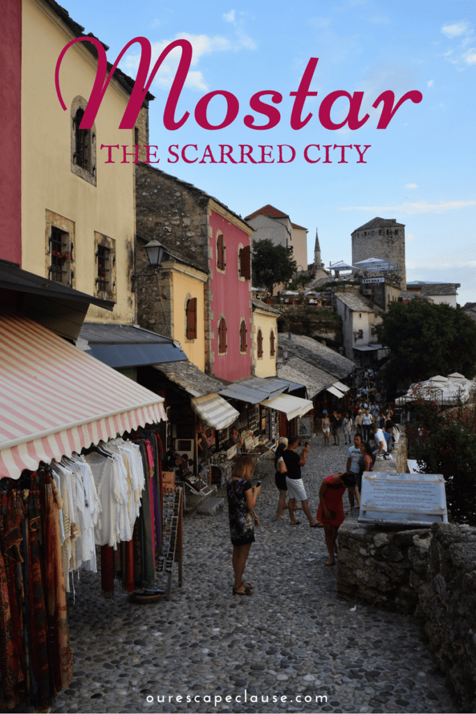 photo of shops in mostar bosnia herzegovina old town, maroon text reads "mostar the scarred city"