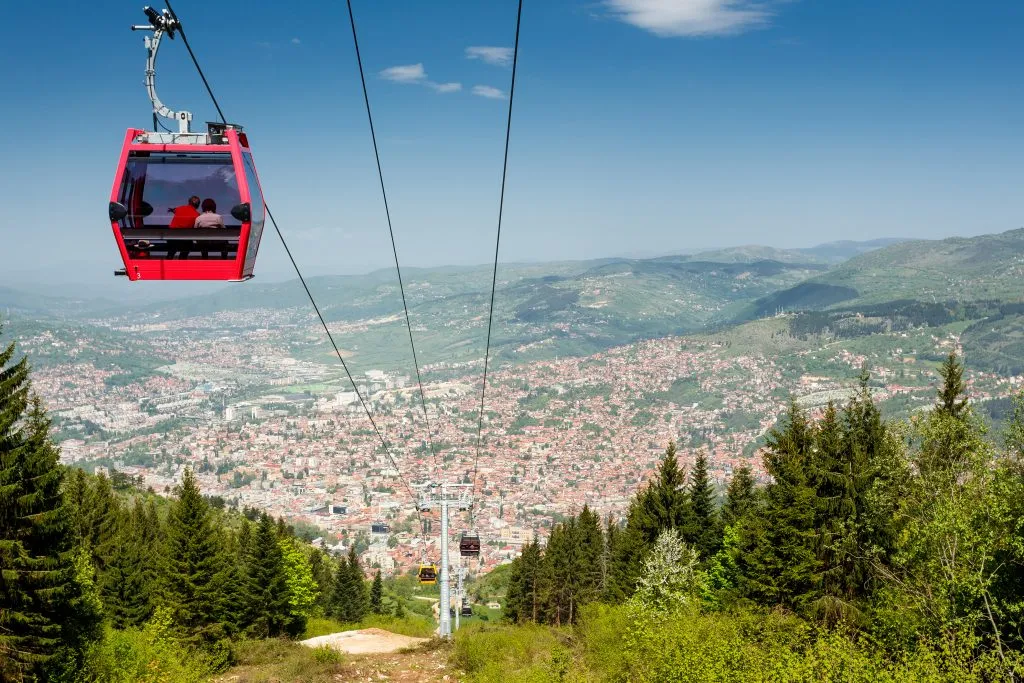 red mount trebevic cable car with sarajevo in the background, one of the fun things to do in sarajevo bosnia