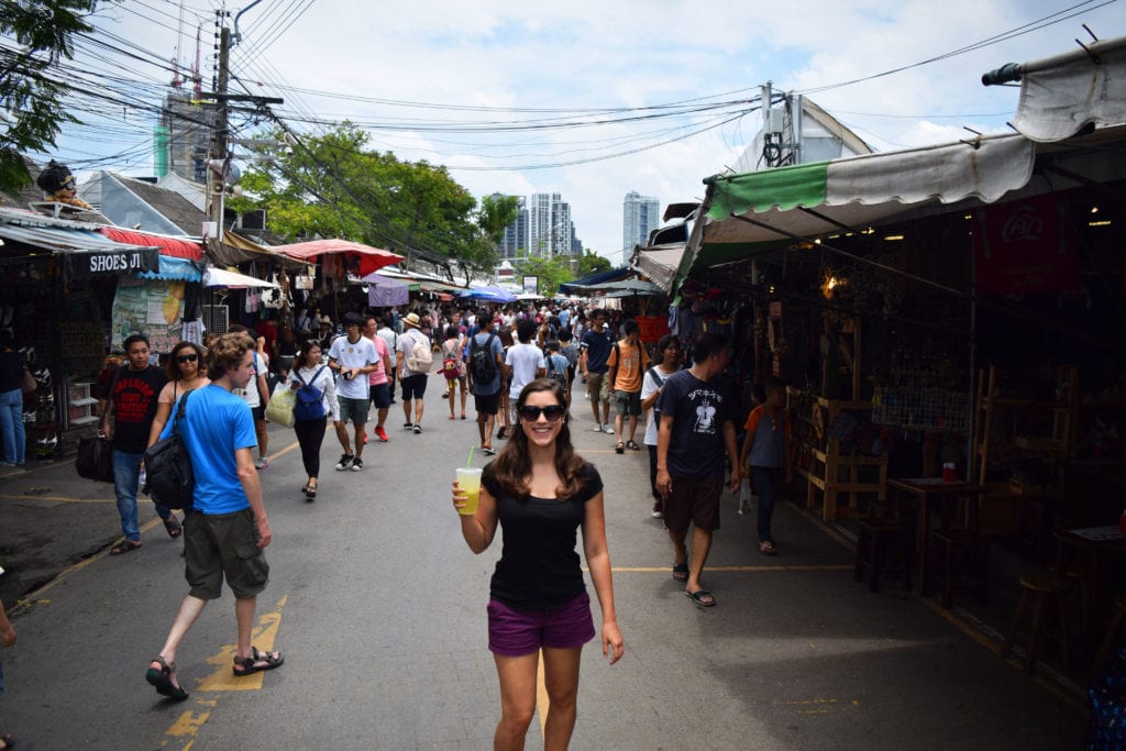 kate storm in chatuchak weekend market holding a passion fruit shake--one of our favorite bangkok travel tips is to drink lots of passion fruit shakes
