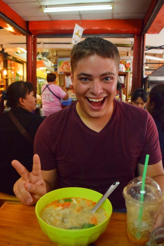 jeremy storm eating a bowl of soup at the chatuchak market in bangkok thailand