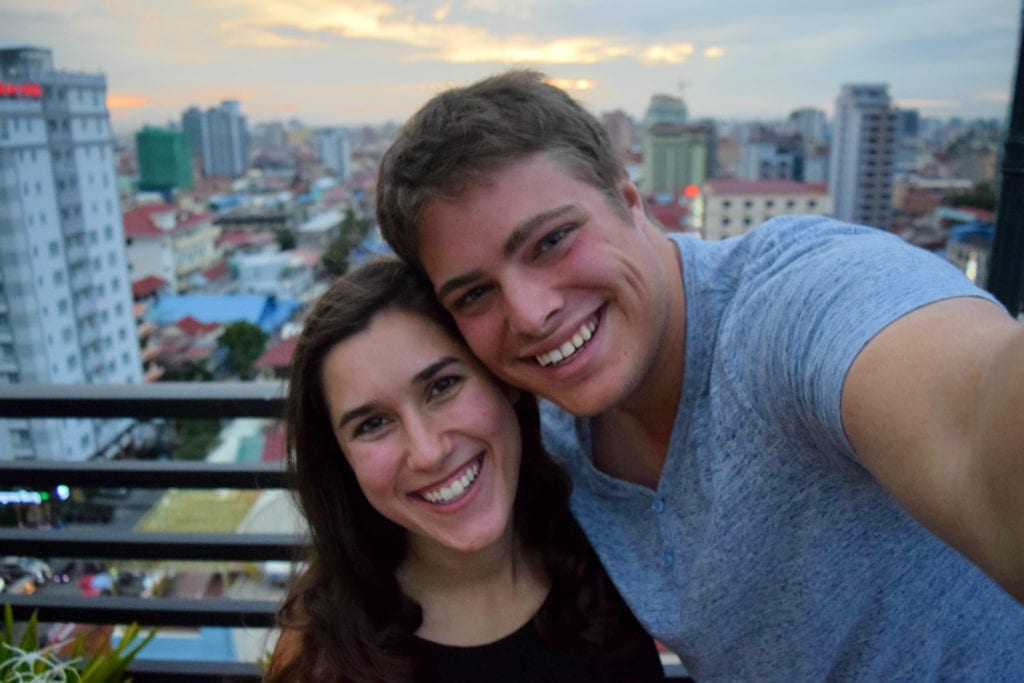 kate storm and jeremy storm taking a selfie at a rooftop bar in phnom penh, an affordable part of their cambodia travel budget