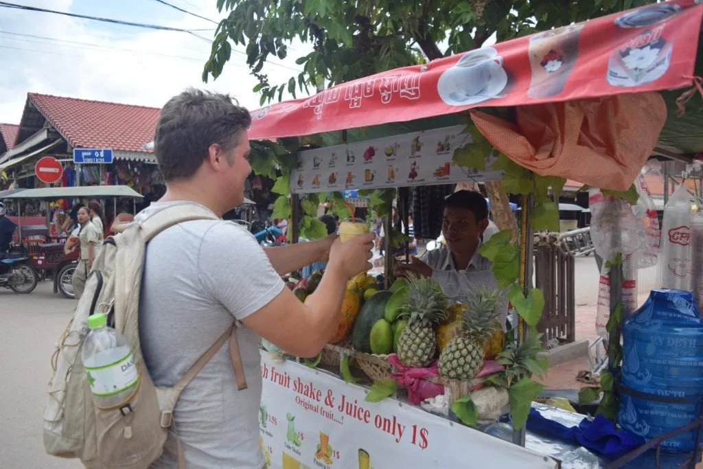 jeremy storm purchasing fruit juice from a street stall in siem reap cambodia