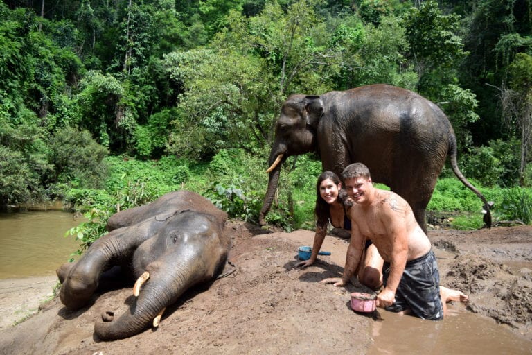 kate storm and jeremy storm with two elephants bathing them in thailand when backpacking the world