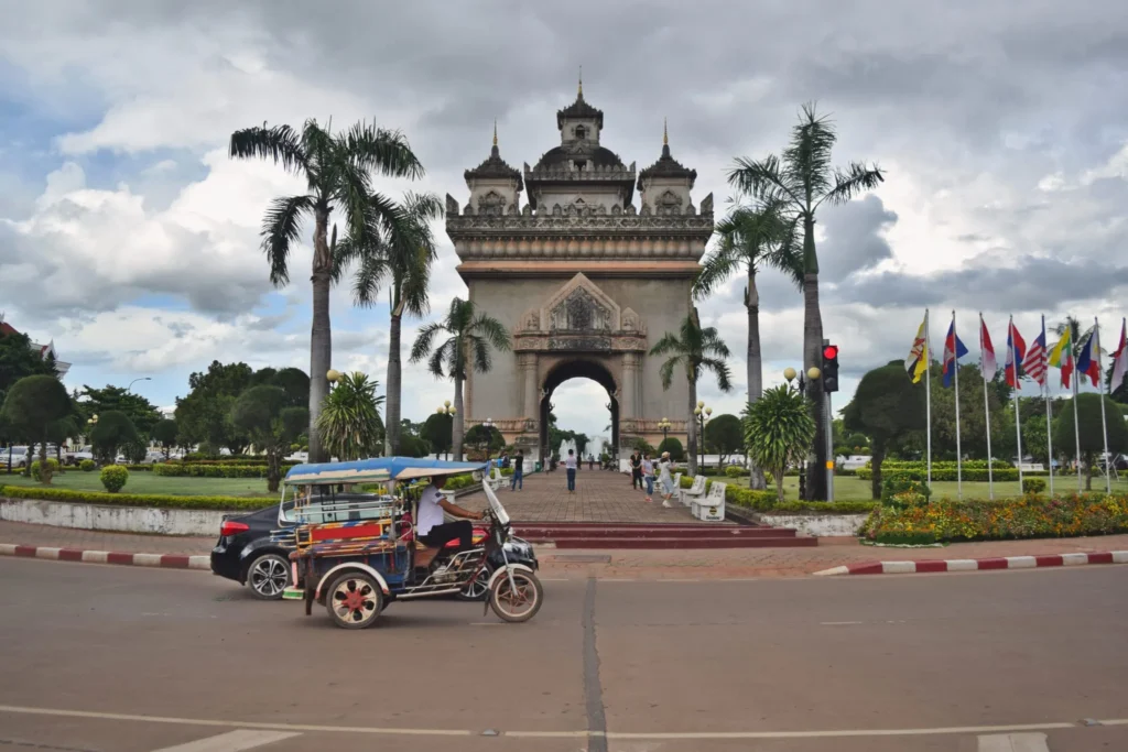 patouxi victory gate, one of the best places to visit in vientiane laos, with a tuk tuk parked in front of it