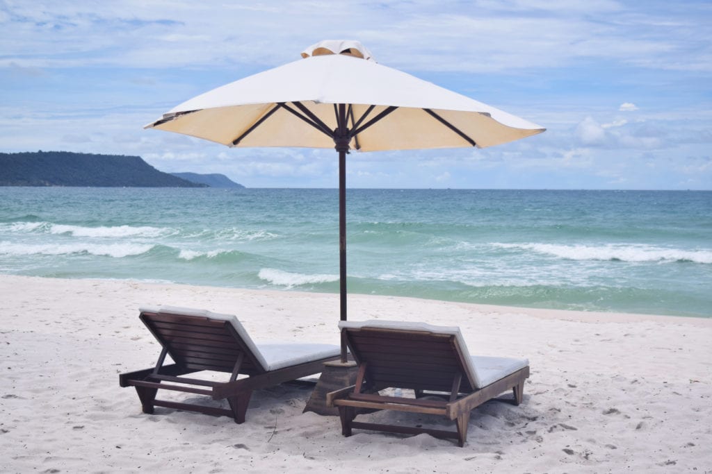 two lounge chairs under a white umbrella at sok san beach resort as seen when visiting koh rong cambodia