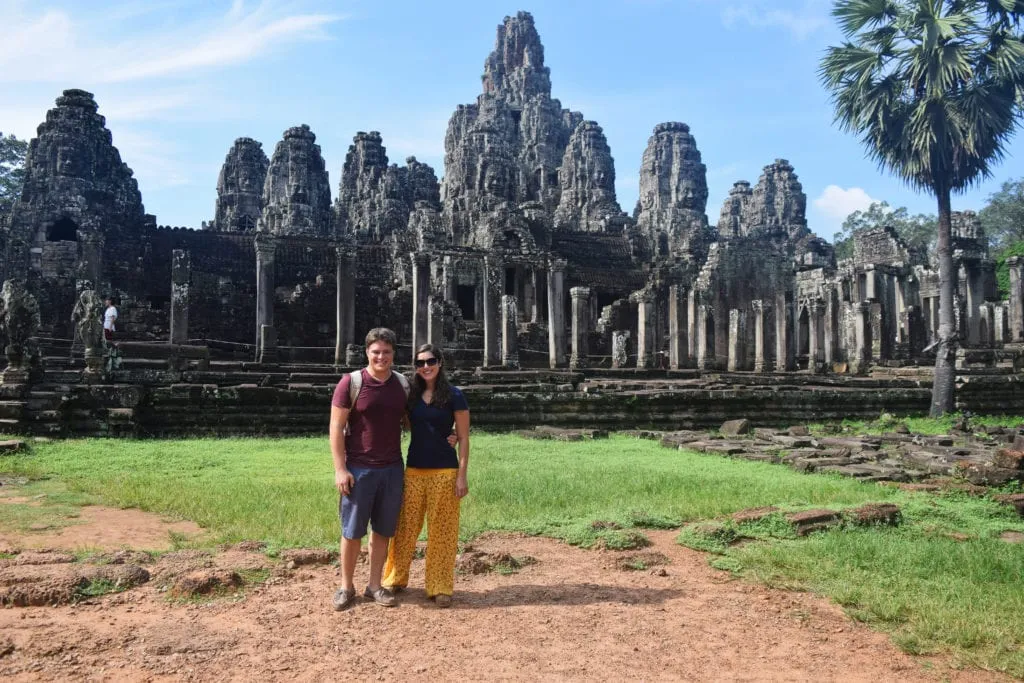 kate storm and jeremy storm standing in front of a large temple when visiting angkor wat cambodia