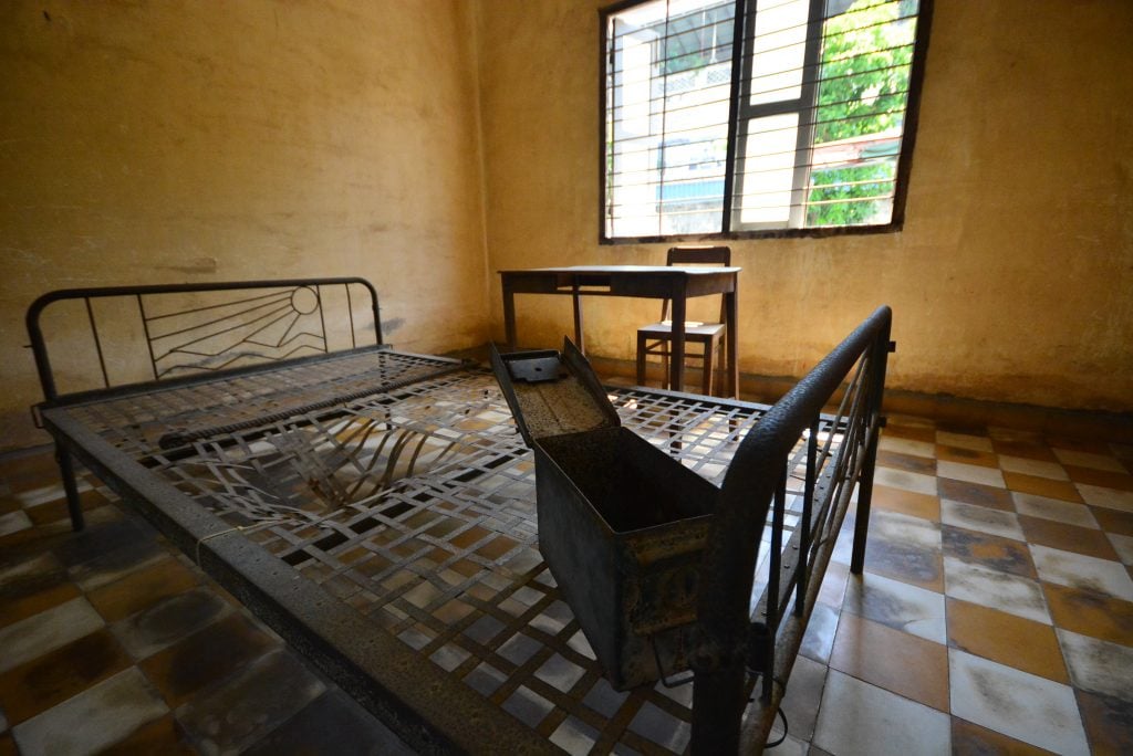 prison cell in tuol sleng genocide museum with wire bed