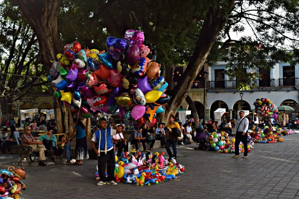 man selling balloons from a large bunch in the zocalo oaxaca de juarez