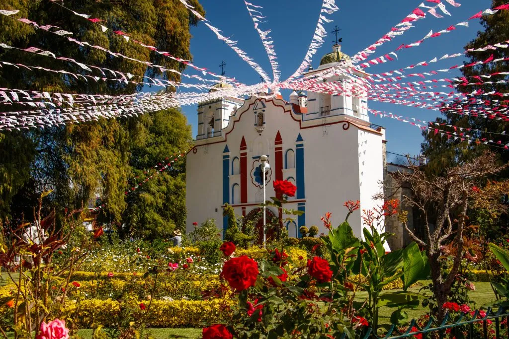 colorful church in the region of oaxaca mexico with flags dangling from it