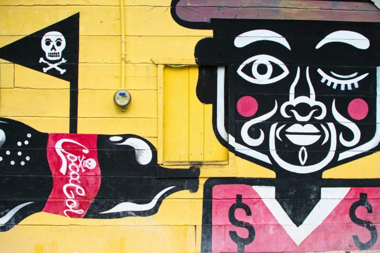 mural of a man holding a coca cola on a yellow background, one of the best things to see holbox island mexico travel budget