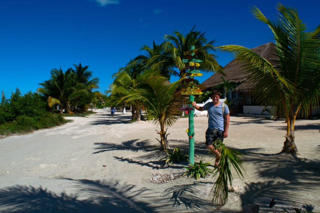 Jeremy storm standing in town next to a signpost in holbox