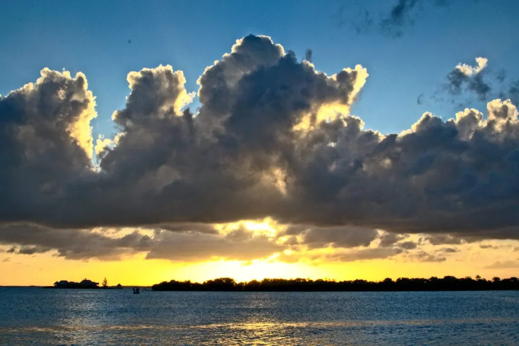 sunset over the water on a partly cloudy evening in placencia belize