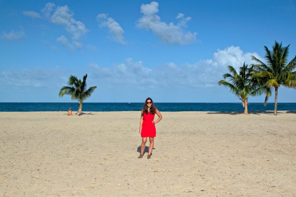 kate storm in a red dress standing on the beach in placencia belize