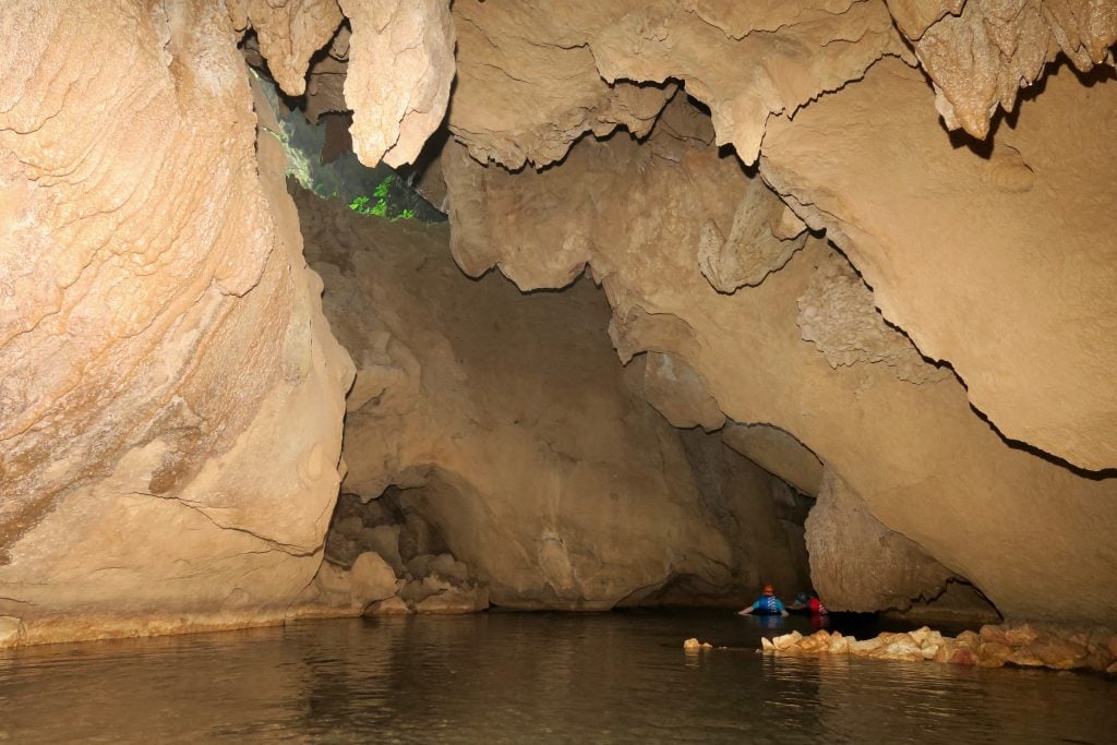 view of people cave tubing in belize with rock formations over them
