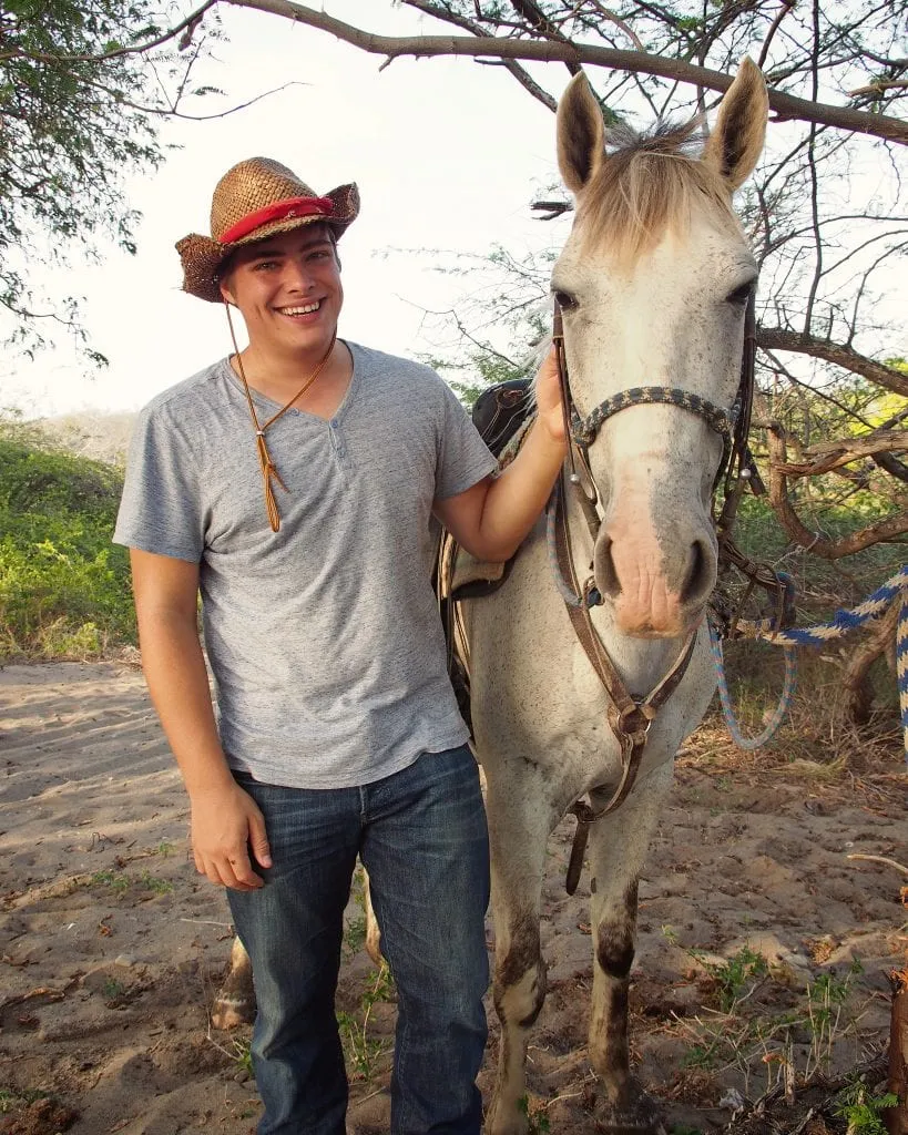 jeremy storm wearing a cowboy hat and standing with a white horse san juan del sur nicaragua