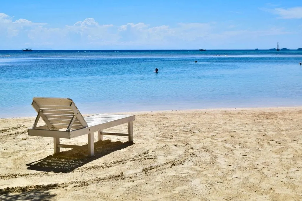 photo of a white lawn chair on a beach in utila--views like this are a very affordable part of a honduras travel budget
