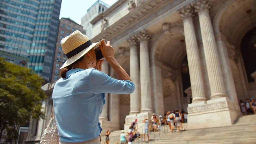 woman in a blue shirt taking a photo on the steps on the met, an iconic stop during a weekend in new york itinerary