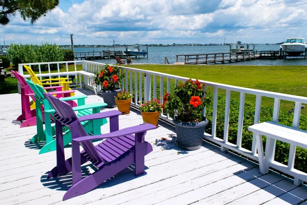4 colorful beach chairs on a white deck overlooking the Bogue Sound in Atlantic Beach NC