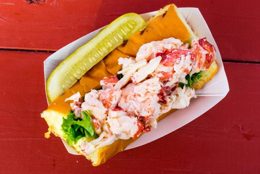 cold lobster roll as seen from above sitting on a red picnic table
