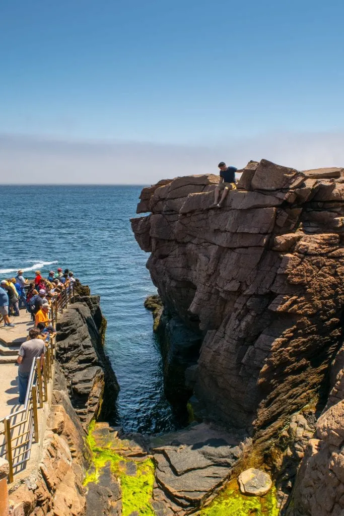 jeremy storm perched on a ledge overlooking thunder hole, one of the best things to see in acadia national park