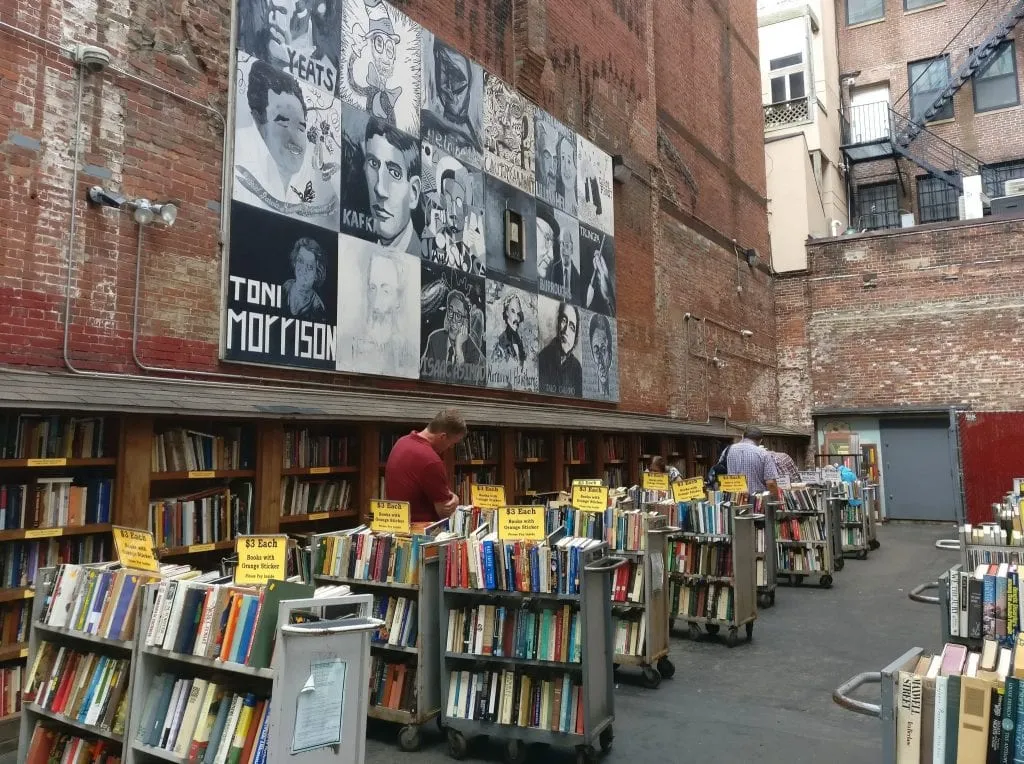 Exterior section of Brattle Bookshop in Boston MA with bookshelves and a mural nearby--one of the best things ot do in Boston MA