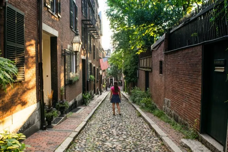 kate storm standing on acorn street in boston massachusetts, one of the most romantic getaways in usa