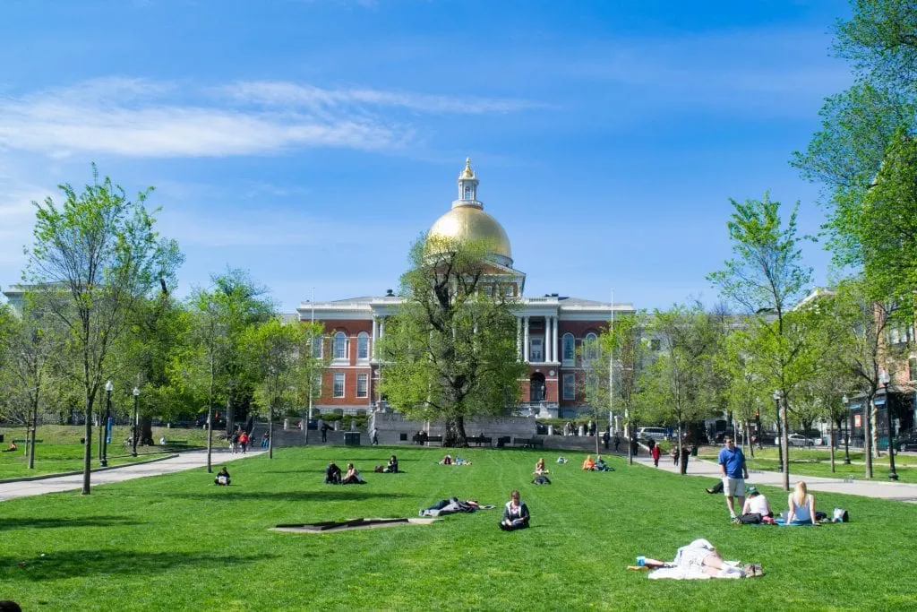 view of the massachusetts state house gold dome with a lawn on the boston common in the foreground, one of the best things to do in boston in one day