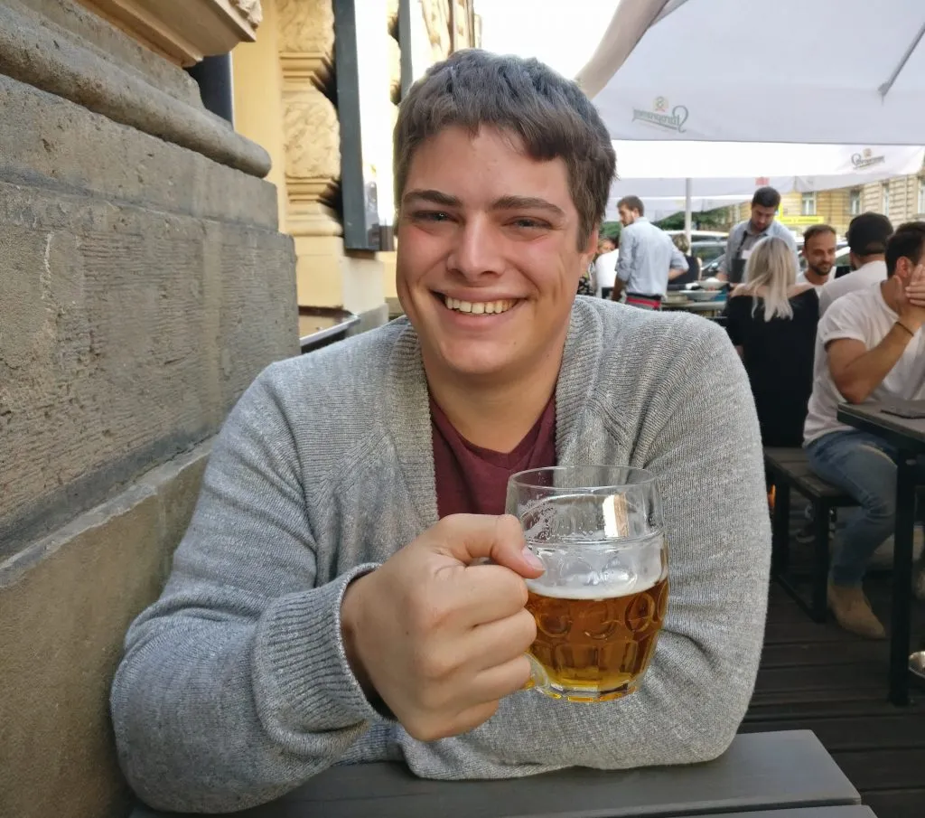 jeremy storm drinking a beer at a restaurant in prague czech republic with a gray sweater on