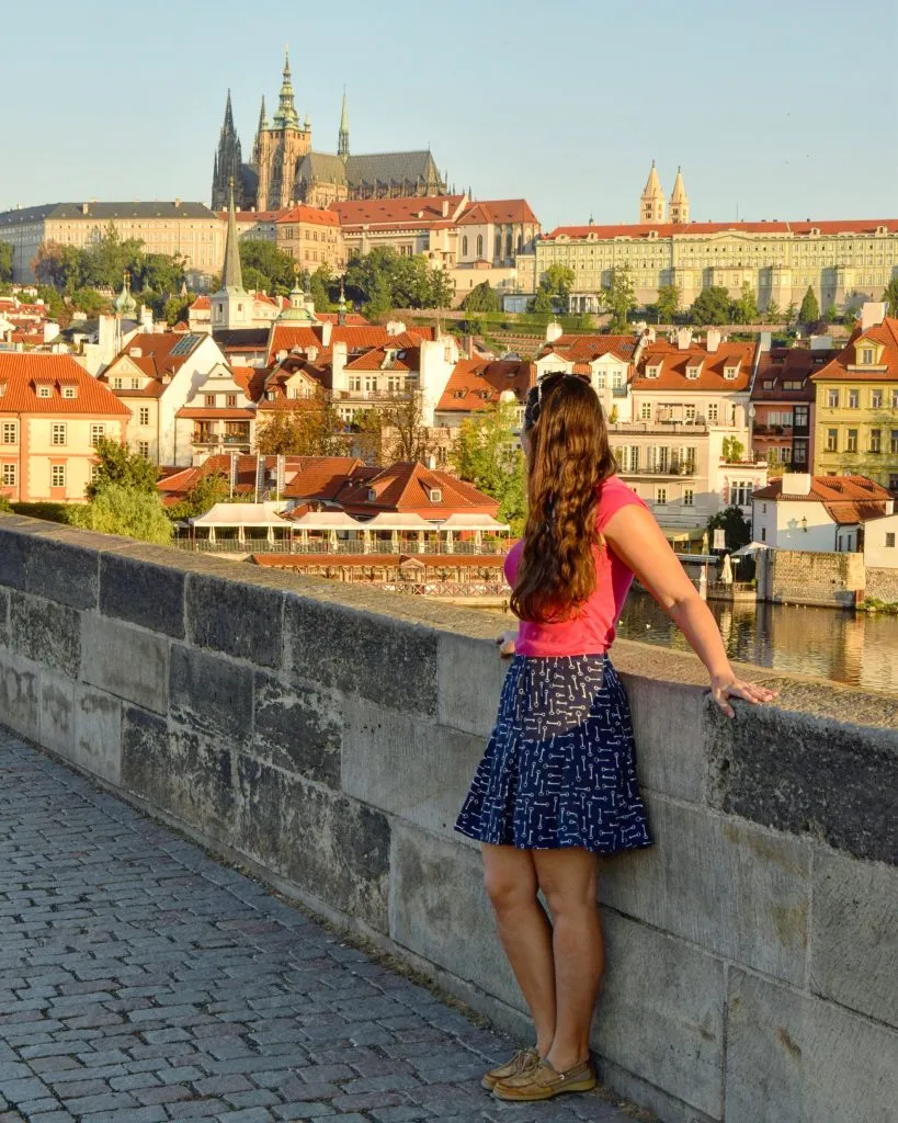 kate storm standing on charles bridge prague czech republic lookint at prague castle in the distance