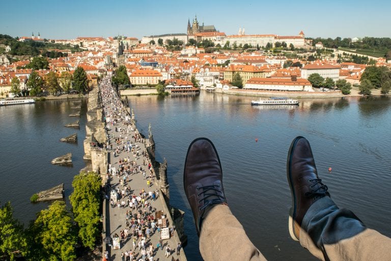 jeremy storms feet overlooking charles bridge from a tower one of the best views in prague and cheap to access when traveling prague on a budget