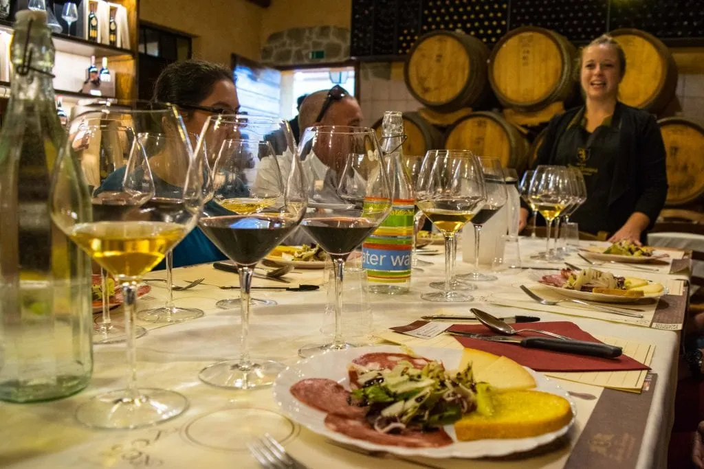 wine tasting in tuscany with several glasses on wine and a plate of food set out