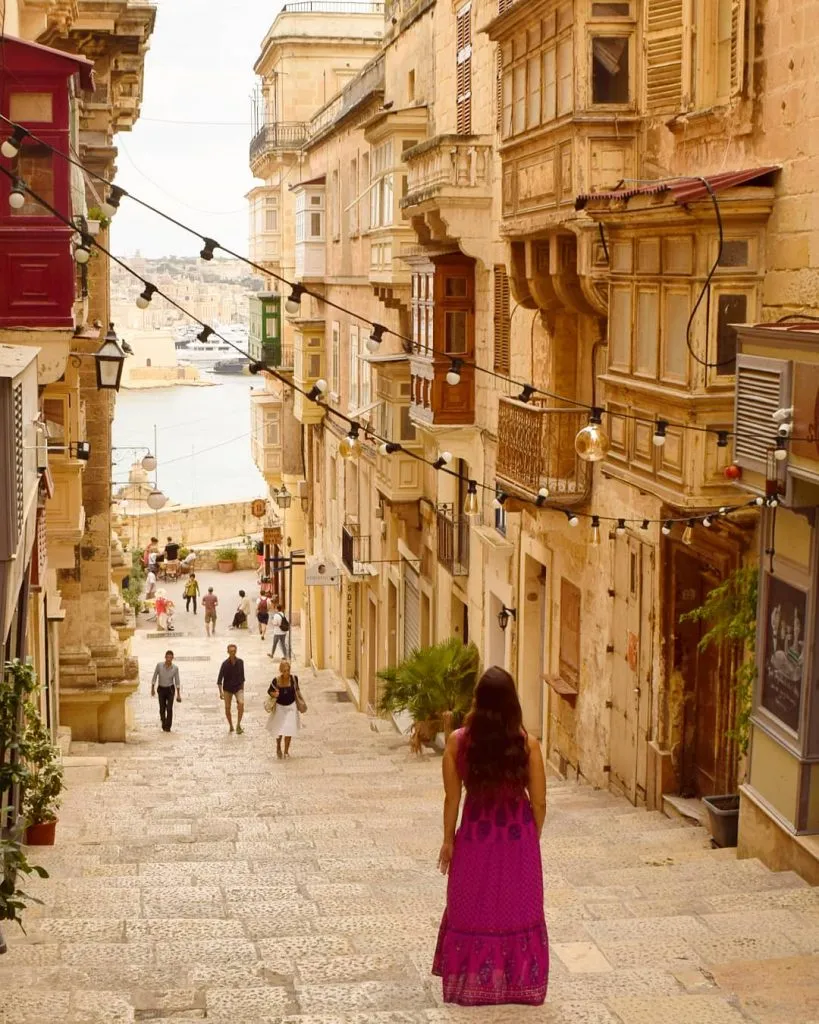 kate storm wearing a pink dress on a side street in valletta malta