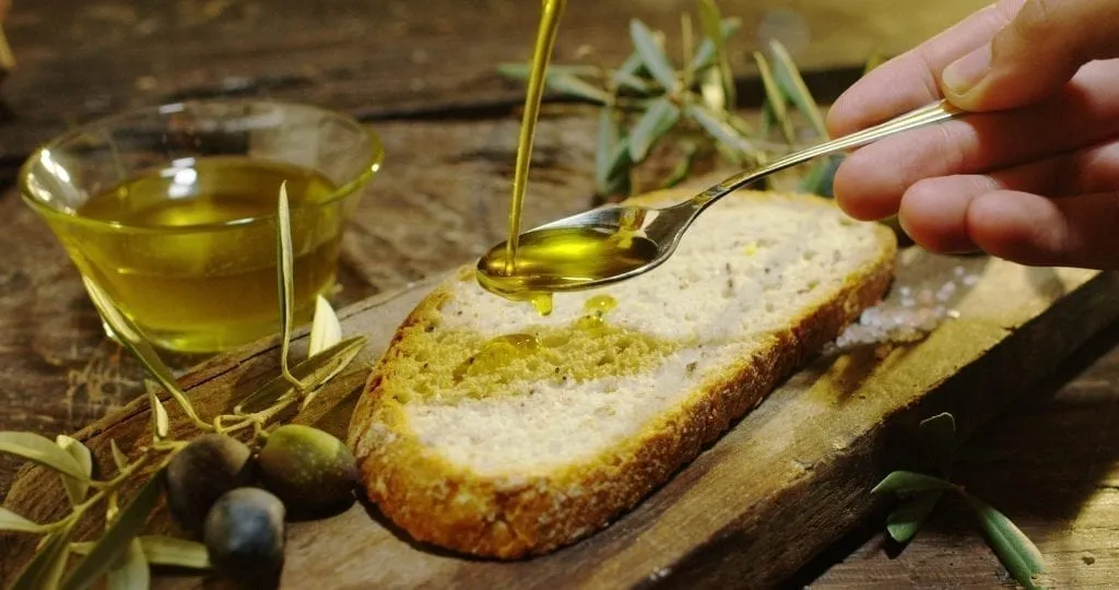 Olive oil being poured over bread via a spoon, one of the best things to eat in Florence Italy