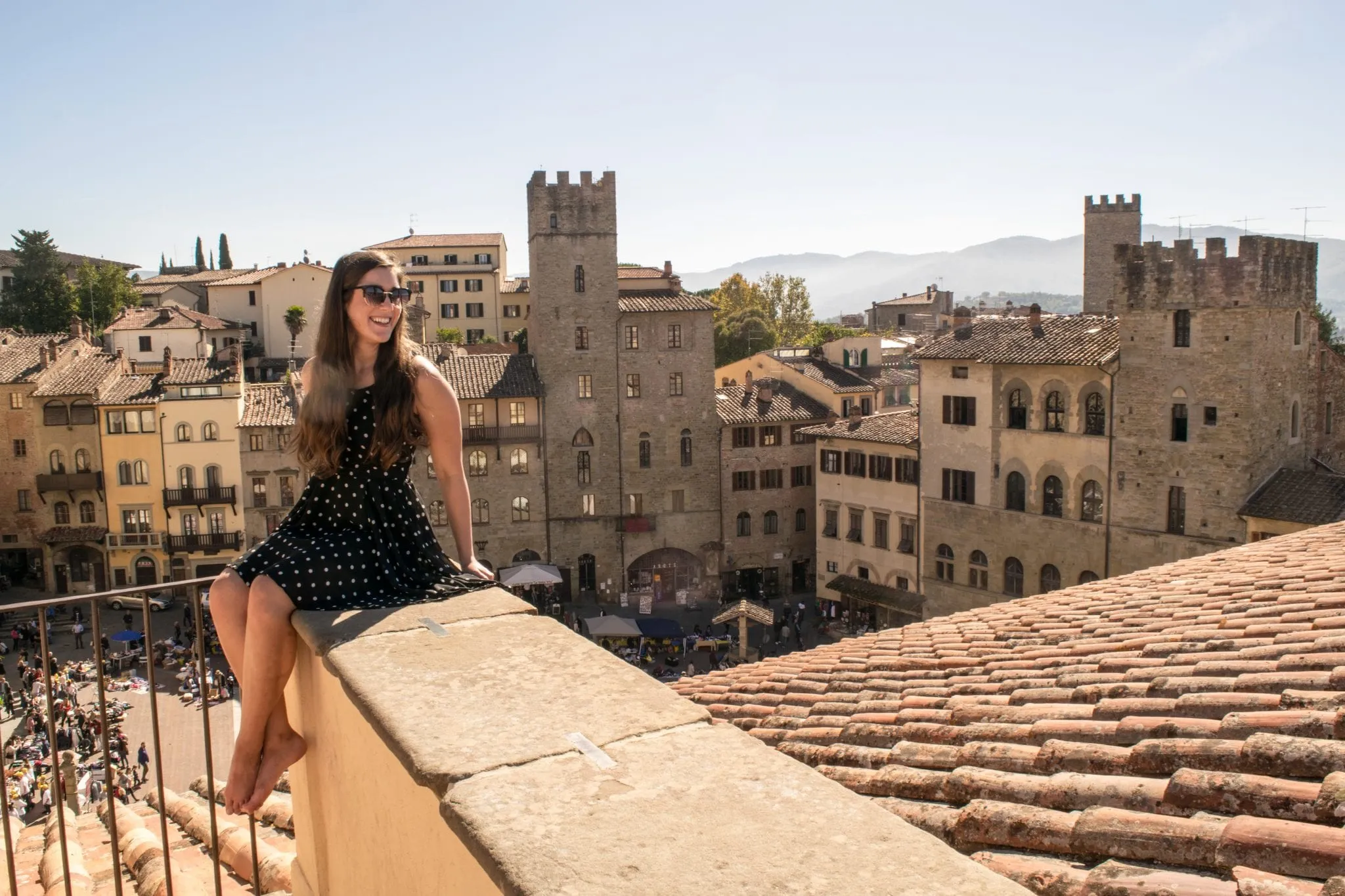 Kate Storm sitting on a ledge overlooking Arezzo, one of the best day trips from Florence